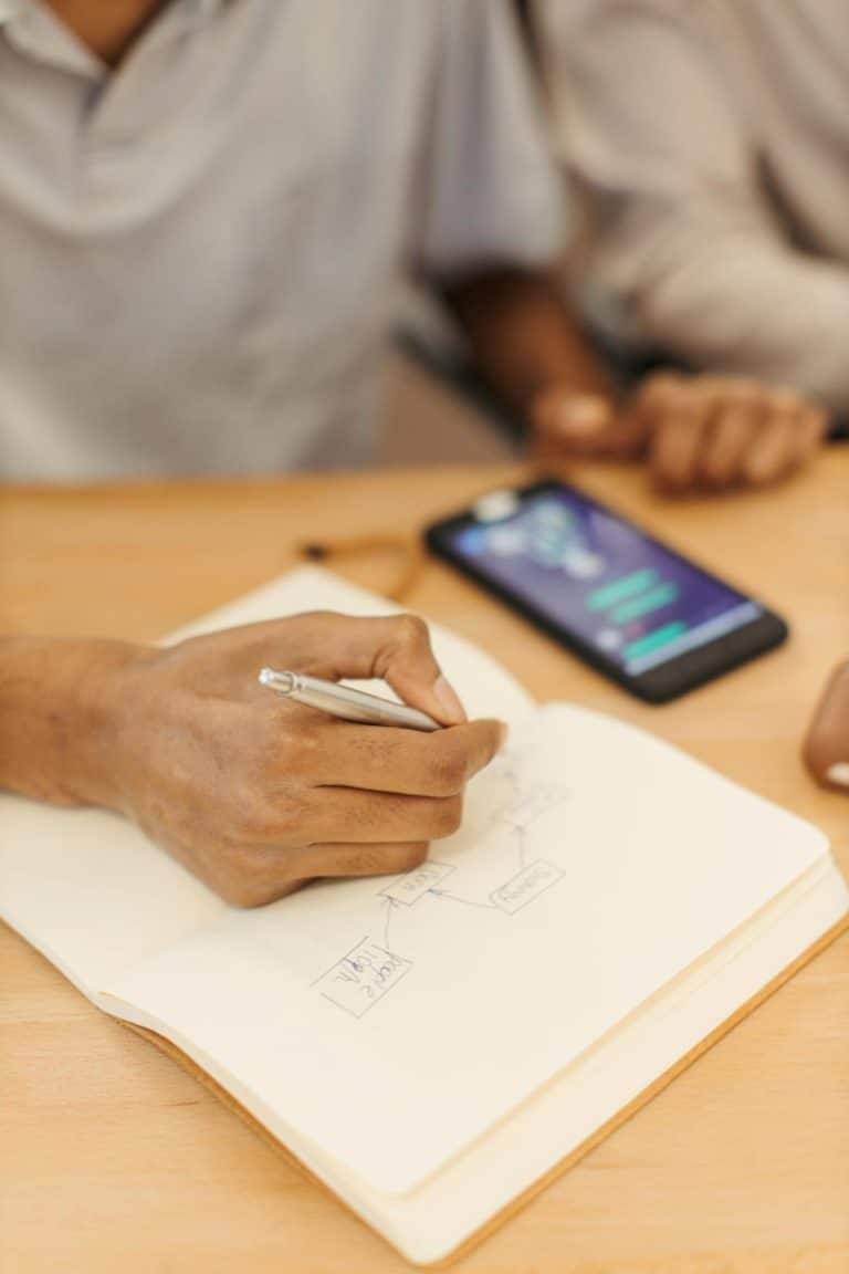 Noter les numéros utiles dans un carnet, un smartphone à côté — mémo des numéros d'urgence et lignes d'écoute pour les familles